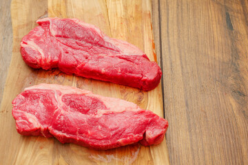 Fresh strip loin steak on a wooden cutting board. Premium product of meat industry. Juicy beef cut....