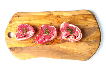 Three fresh lamb loin chop with herbs on a wooden board and white background. Meat industry product, butcher craft and skill example. Top quality meat.