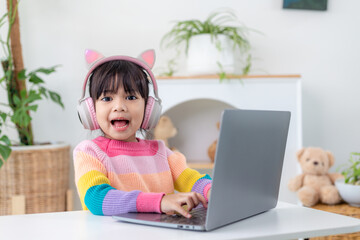 Smiling little Asian girl have a video call distant class with teacher using laptop, social distance during quarantine isolation during the Coronavirus