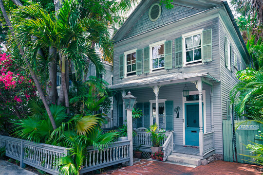 Key West, USA - 04.30.2019: Beautiful old wooden house in spanish colonial style with a porch. Wooden district of Key West, Florida. Palm trees in the garden. Beautiful sunny day in tropical paradise.
