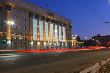 Fototapeta na wymiar mayor's office of novosibirsk with garlands at night and a trail of headlights from moving cars