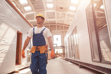 Fototapeta premium Handsome man builder walking down the building under construction