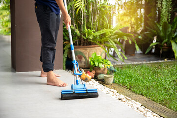 The lower part of the man cleaned the janitor's floor with caution, the floor was wet.at home