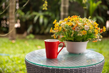 Coffee cup on wooden with flower in vase on table, in the garden on summer