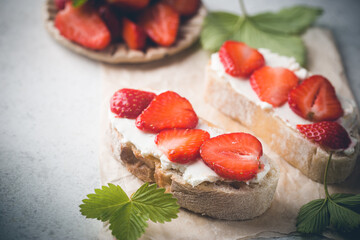 Strawberries sandwiches with cream cheese and on paper, light background