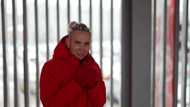 Close-up portrait of a happy homosexual man with dreadlocks in his hair outside in a warm red jacket