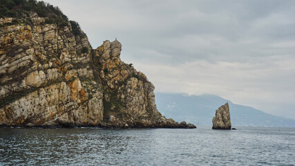 A lonely rock in the sea on the background of the Crimean mountains.