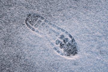 Footprint of boot in the snow, shoes for winter walking in cold weather and ice