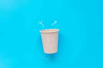 Ein Pappbecher mit Arme hoch und einem lächelnden Gesicht. Illustration, Idee, nachhaltige Lebensweise.