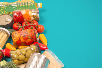 Food donations and different groceries on blue background with copy space - pasta, vegatables, canned food, baguette, cooking oil, tomatoes, cheese. Food bank, food delivery concept. Selective focus