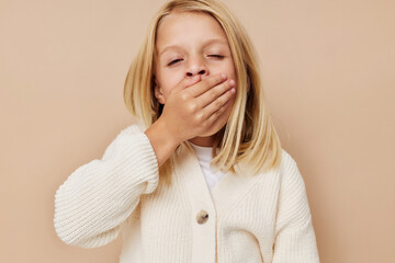 Beautiful little girl in a white sweater on a beige background