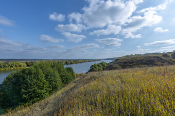 Naklejka premium Autumn landscape with a view of the river and endless expanses of fields. Panoramic landscape with river and field and trees.