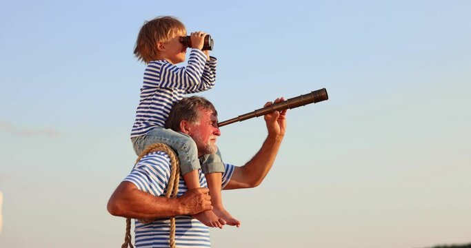 Grandfather and boy with telescope having fun outddor against blue summer sky. Explore and discovery concept. Slow motion