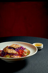 Healthy vegetable salad with grilled chicken in a white plate on a black background