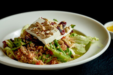 Quinoa and feta salad in white plate on black background