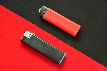 Flat lay and copy space. At the junction of the black and red background lies a black and red lighter. The concept of conservatism and minimalism. Classic colors in product advertisements