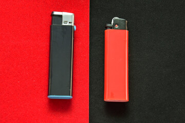 Flat lay and copy space. At the junction of the black and red background lies a black and red lighter. The concept of conservatism and minimalism. Classic colors in product advertisements