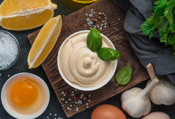 Mayonnaise, and ingredients for cooking: eggs, lemon and butter on a black background. Homemade mayonnaise. Top view.