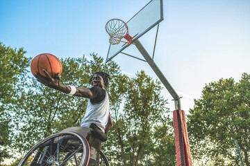 African basketball player on his wheelchair plays with the ball demonstrating his determination and...