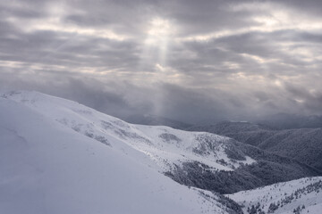 Fototapeta na wymiar Snow-covered mountain slopes at sunset. Winter mountain landscape.
