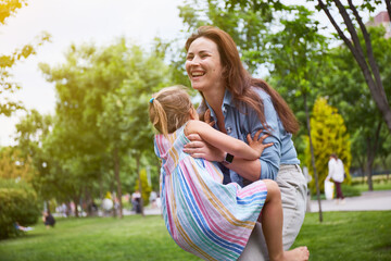 Happy Mother and her daughter playing in the park. Enjoying summer. Happy parenthood