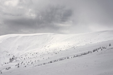 Snow-covered mountain range against the backdrop of a cloudy sky. Alpine skiing track. © Oleksiy