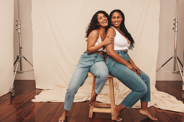 Girlfriends laughing together in a studio - obrazy, fototapety, plakaty