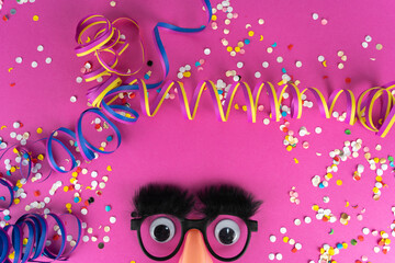 Funny face mask with big eyes, confetti, streamers and pink background