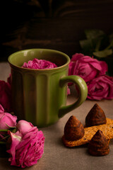 Coffee in a green mug and roses on a dark background. Romantic stylish composition for a greeting card