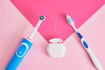 dental floss, electric and plastic toothbrushes on a pink background, which brushes are more effective in cleaning