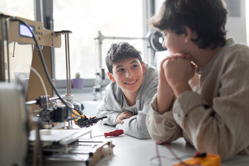 Young engineering students using a 3D printer