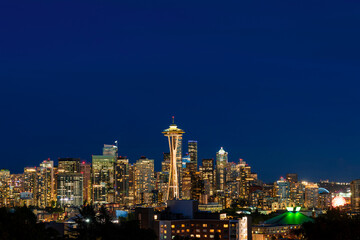 Obraz premium Seattle skyline panorama with iconic view observation tower called Space Needle as seen from Kerry Park. Skyscrapers of financial downtown at night, Washington, USA. A vibrant business neighborhood
