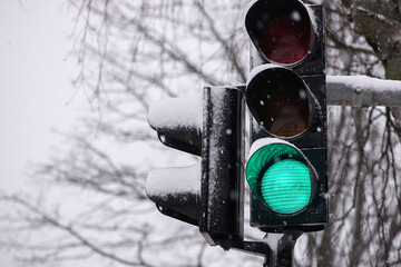 A city crossing with a semaphore. Green light in semaphore during winter snowy day