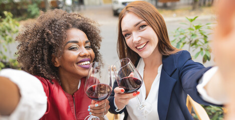 Young women, coming from different culture enjoying time together while drinking red wine in order...