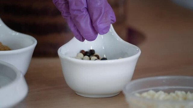 Pastry chef takes small chocolate balls out of dishes. A close-up of a well hand.