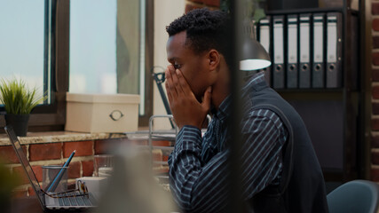 Fototapeta premium Anxious worker finging put bad news about business project in office. Company accountant worrying about work failure, planning financial report under pressure on laptop. Frustrated man