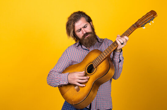 brutal caucasian hipster with beard in shirt play acoustic guitar, music
