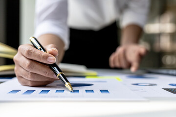 Businesswoman pointing to a chart document showing company financial information, she sits in her private office, a document showing company financial information in chart form. Financial concepts