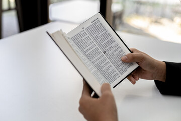 A person is reading the Bible, he is praying to the Bible, he is reading and studying the Bible. Concept of Christianity and Bible Study.