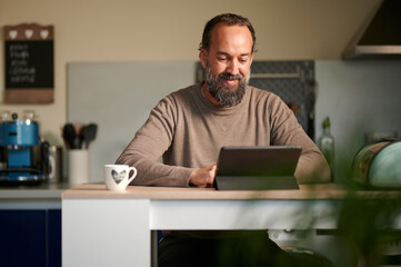 Bearded man using digital tablet in kitchen