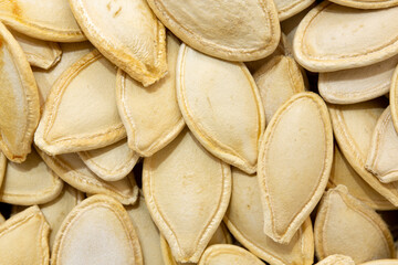 Background photo of pumpkin seed grains. Macro view of roasted pumpkin seeds. Shelled pumpkin seeds...