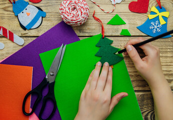 Fototapeta premium Making handmade Christmas toys from felt with your own hands. Step 1. Circle the stencil with a pencil.