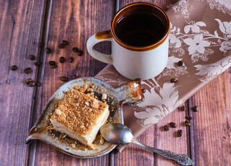 Homemade baked cake Napoleon, Millefeuille. Delicate custard cake. Against the background of a wooden table with a beautiful napkin and whole coffee beans