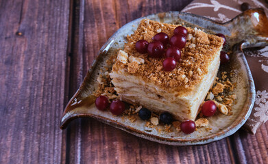 Homemade baked cake Napoleon, Millefeuille. Delicate custard cake garnished with berries. Against the background of a wooden table with a beautiful napkin