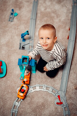 Fototapeta premium Happy kid playing with plastic train on toy railway road at home. childhood education construction concept