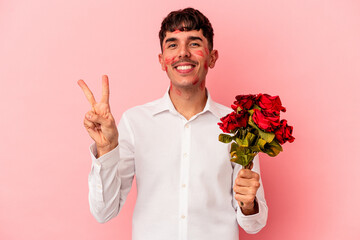 Young mixed race man holding a bouquet of flowers isolated on pink background showing number two with fingers.