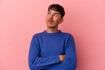 Young mixed race man isolated on pink background dreaming of achieving goals and purposes