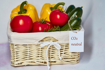 Wicker basket with carbon neutral product label on fresh vegetables.Carbon labeling. Net zero carbon, emissions free. Organic farm products from local market. Fresh tomatoes, cucumbers and bell pepper