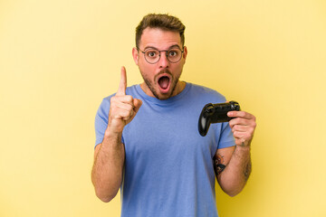 Fototapeta na wymiar Young caucasian man holding a game controller isolated on yellow background having an idea, inspiration concept.