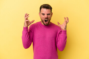 Young caucasian man isolated on yellow background screaming with rage.